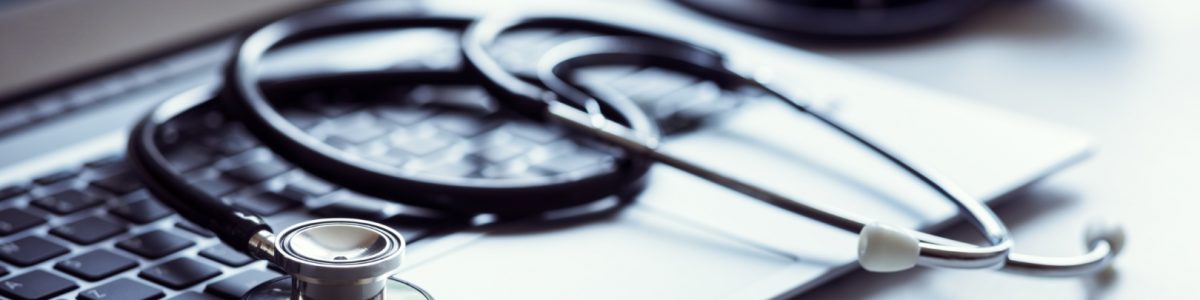 Stethoscope on laptop keyboard in doctor surgery Stethoscope on laptop keyboard in doctor surgery with blood pressure monitor